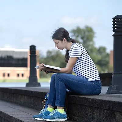 女性在湖边的台阶上阅读.
