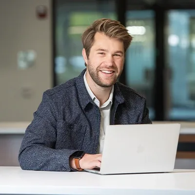 Graduate college student smiling while working on laptop computer