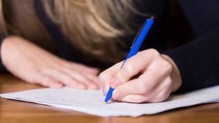 Closeup of a girl writing notes on paper.
