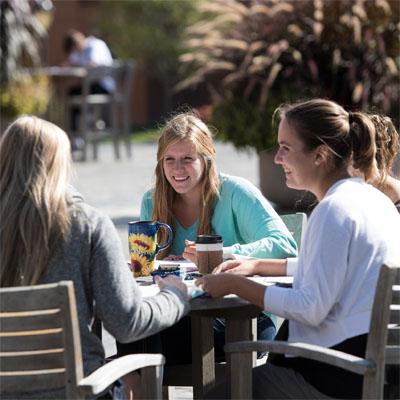 Three female students sitting at a high table outside at Cedarville University